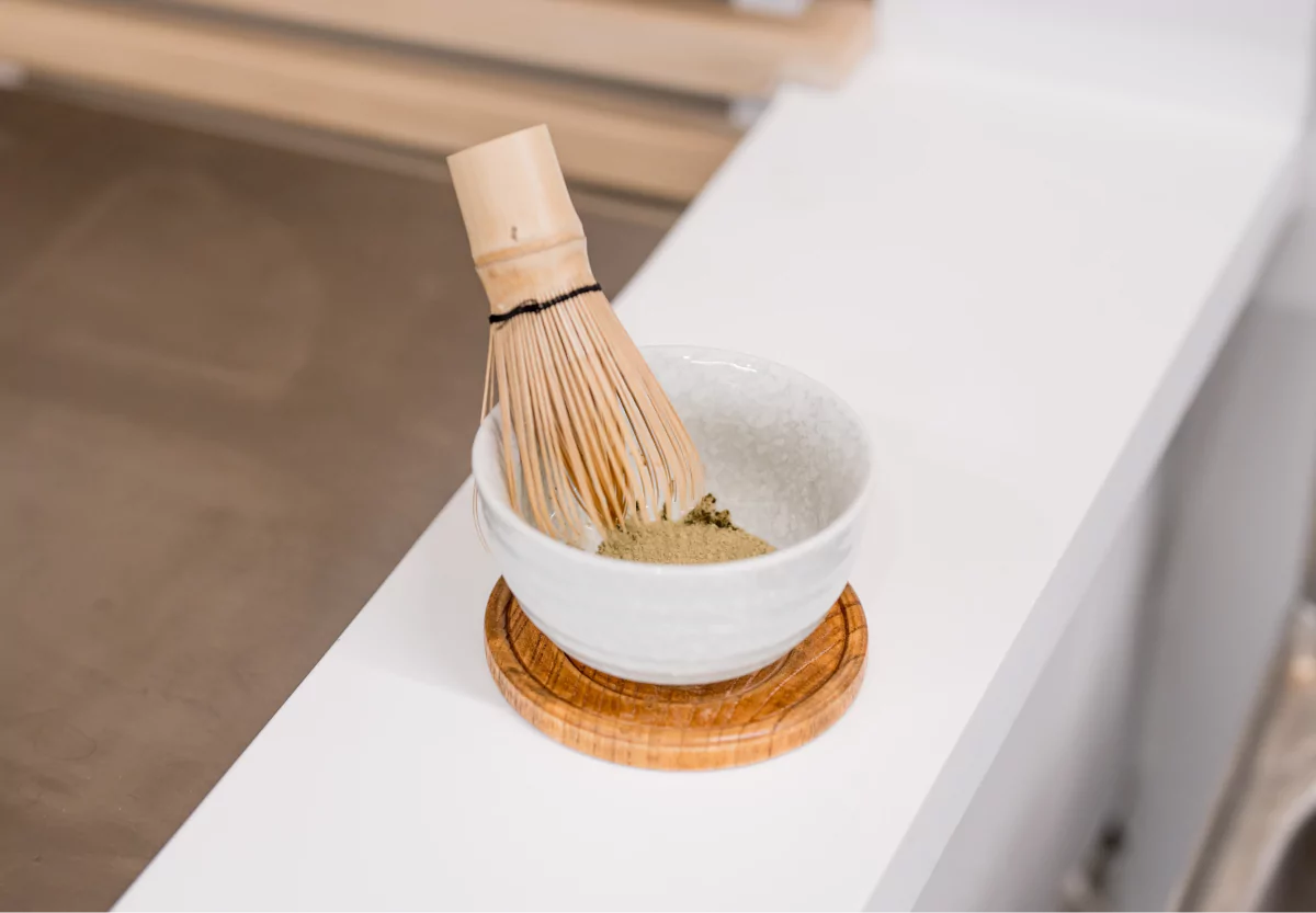 a whisk and a bowl with herbs