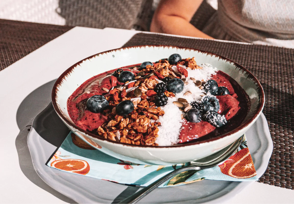 A bowl of yogurt, granola and berries on a brown tablemat