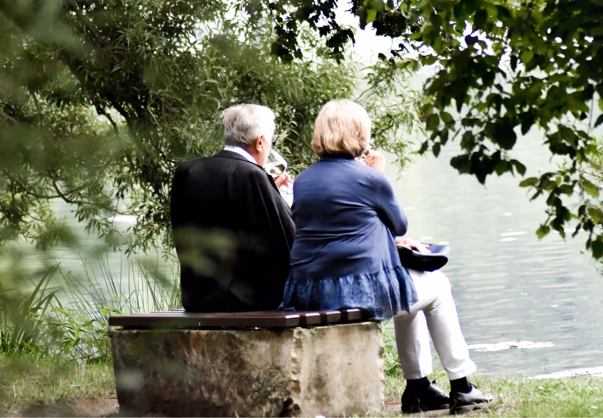 two elderly people drinking wine outside