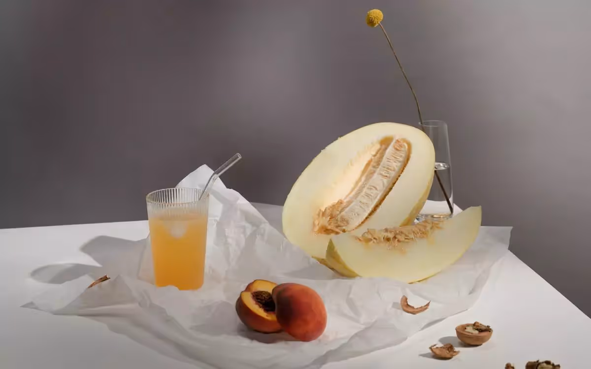a melon, peach and a glass of drink