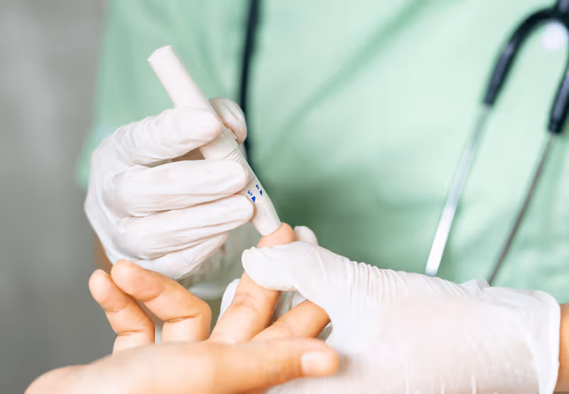 Doctor pricking patient's finger for blood
