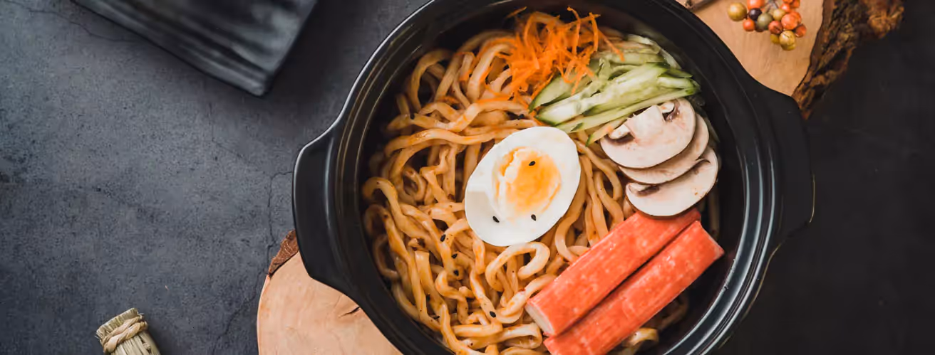 a bowl of noodles, a half of a boiled egg and veggies