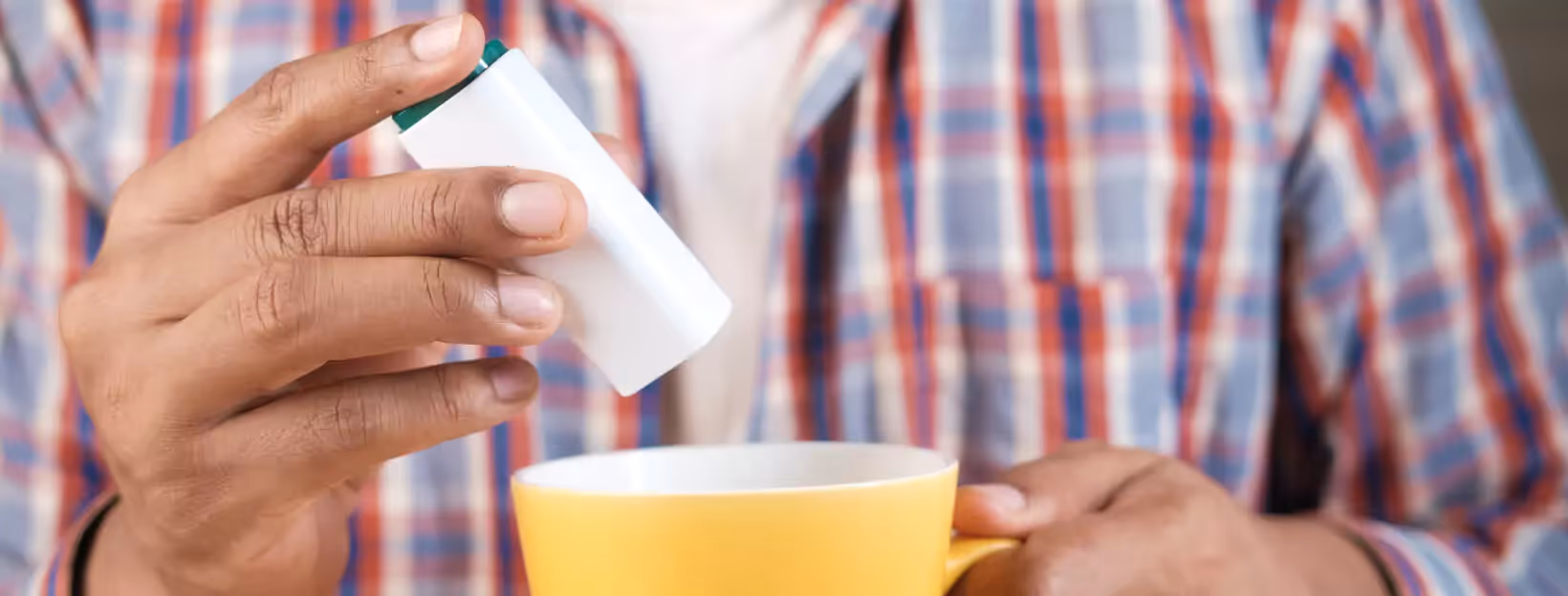 a person adding an artificial sweetener to their drink
