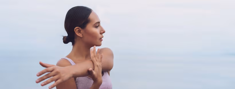 A close-up of a person stretching their arms against a sky blue backdrop