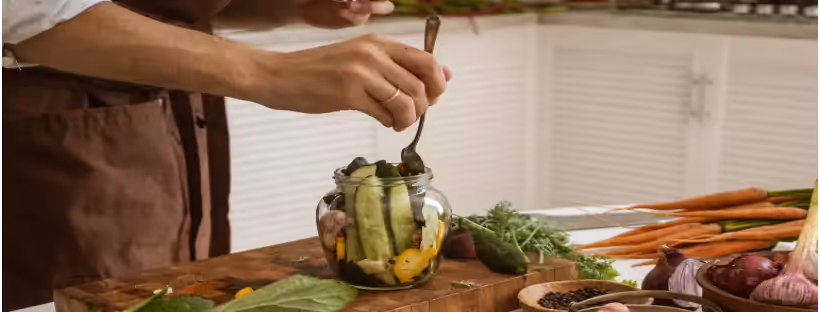 a person putting veggies into a jar
