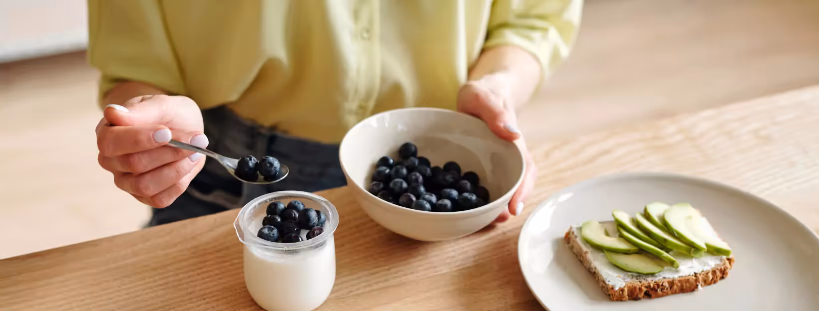 a person adding blueberries to yogurt