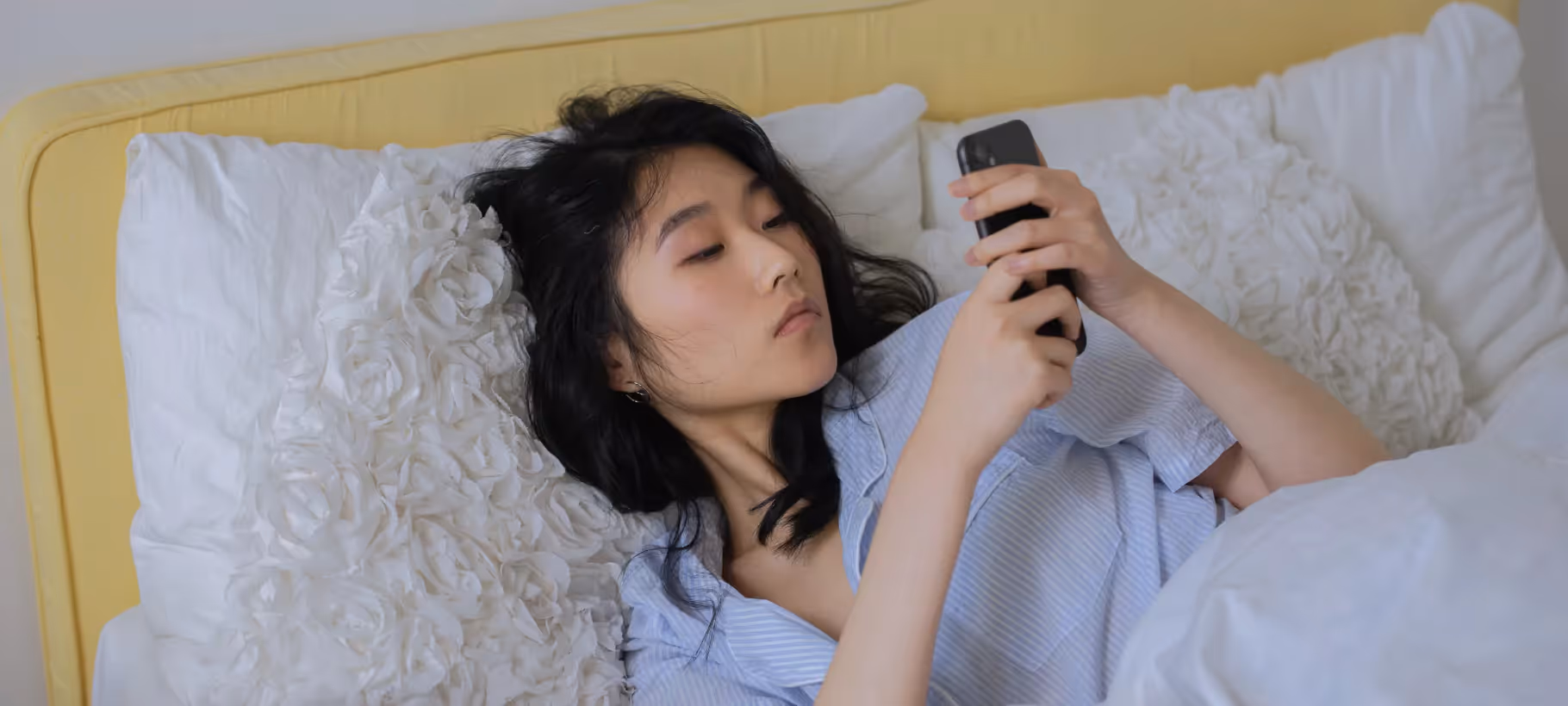 a girl looking at her phone in bed