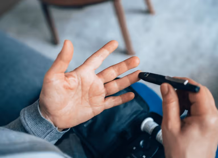 A closeup of a pair of hands using a fingerprick to test blood sugar levels