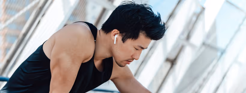 A man wearing earbuds, leaning forward mid-workout