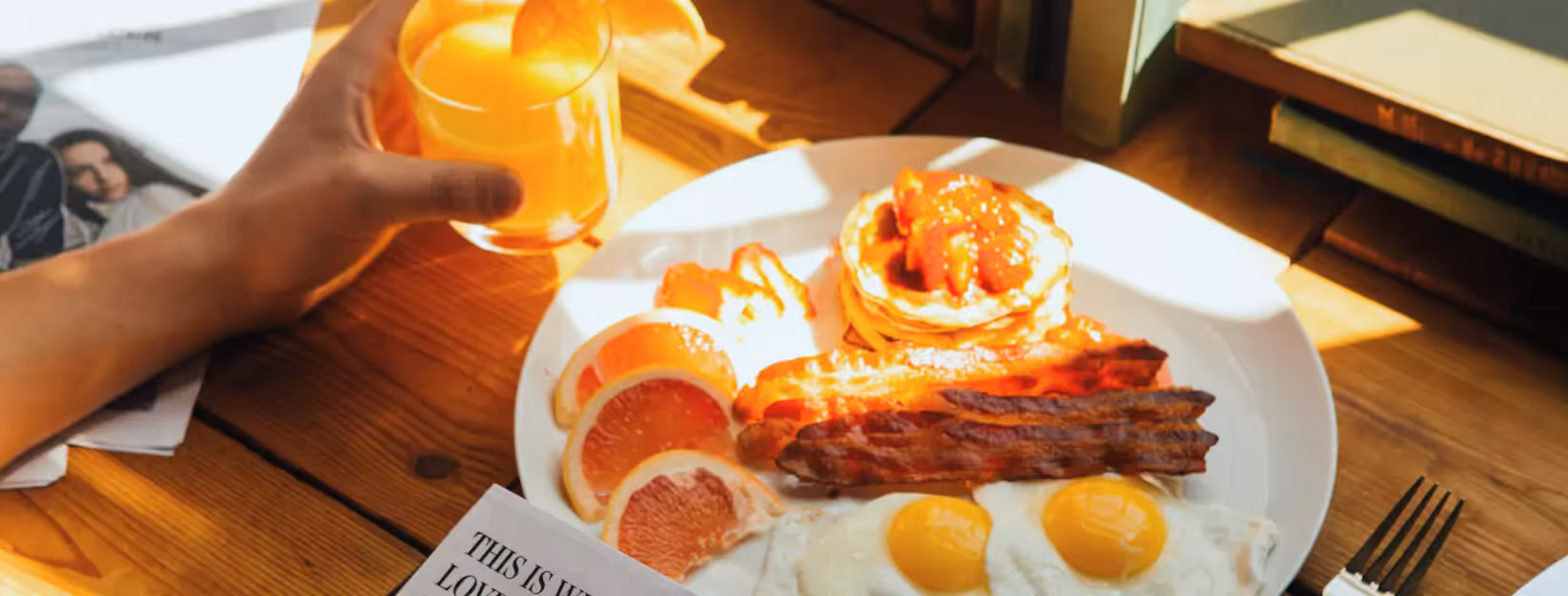 a plate of eggs, bacon, pancakes and slices of grapefruit