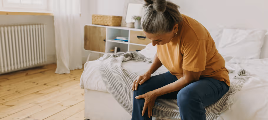 a woman hunched over sitting on a bed
