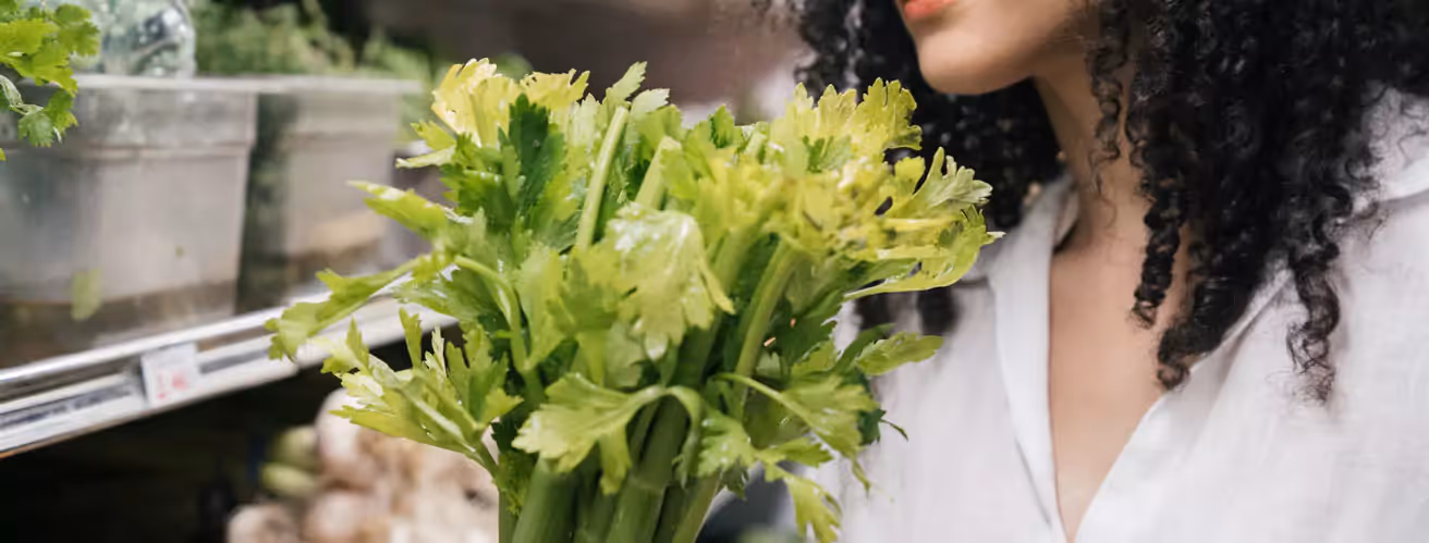 a person picking vegetables including celery at a supermarket