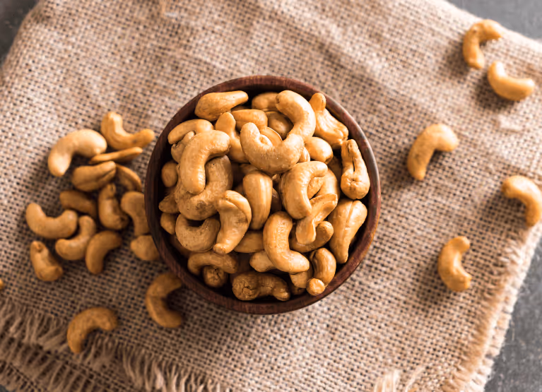Bowl of cashews on top of tan colored linen