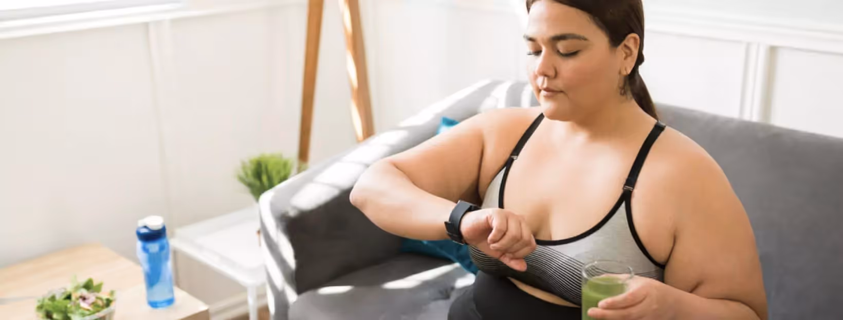 a person sitting on a sofa and looking at her smartwatch