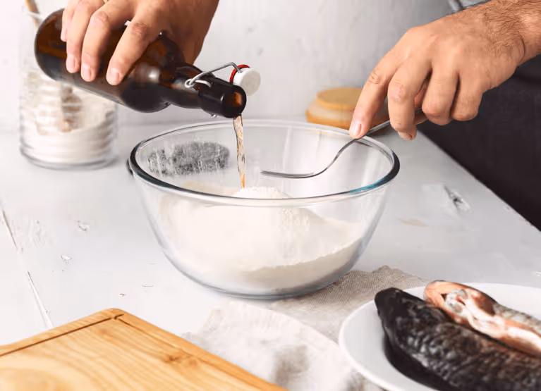 Person pouring beer into bowl of flour