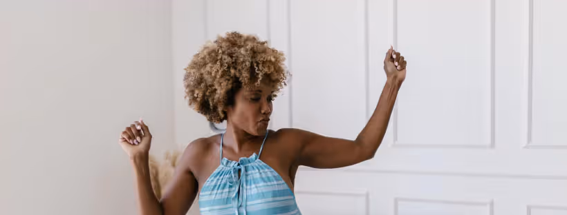 A woman with curly hair in a blue top dancing