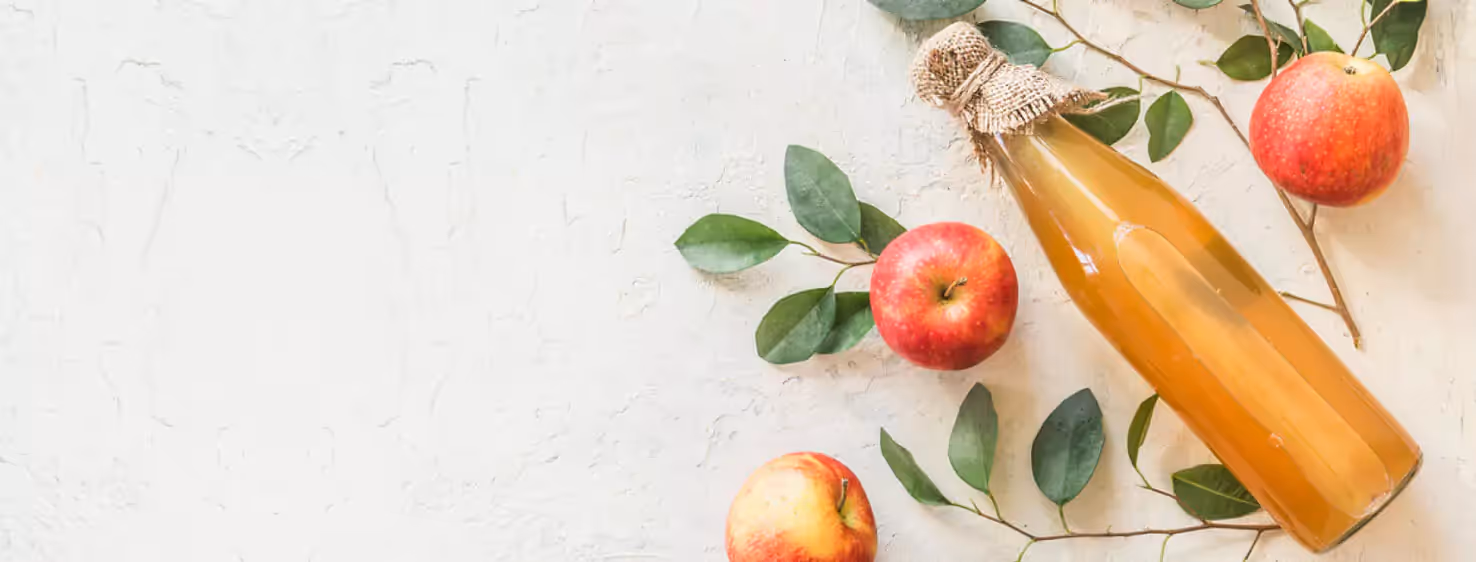 a bottle of apple cider vinegar and apples
