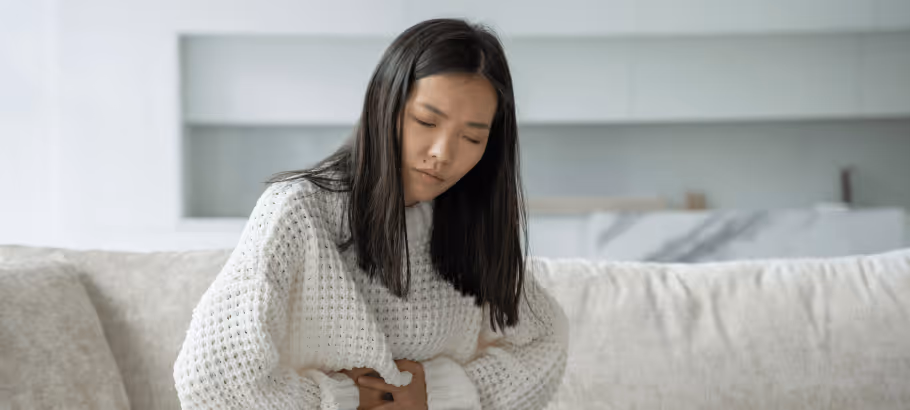 a girl in a hospital gown holding her stomach in pain