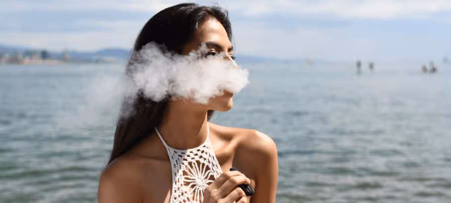 a girl vaping outside with a cloud of smoke around her face