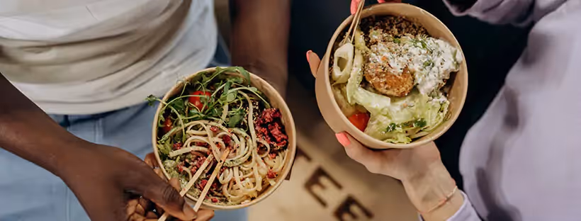 Close-up of two pairs of hands holding bowl lunches