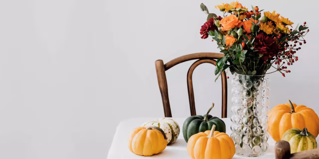 a few squashes and a a vase of flowers on a table