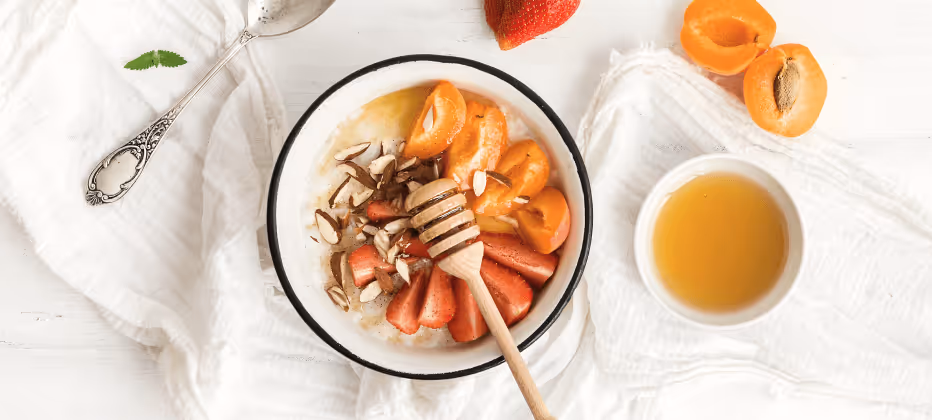 a plate of oatmeal with fruit and honey
