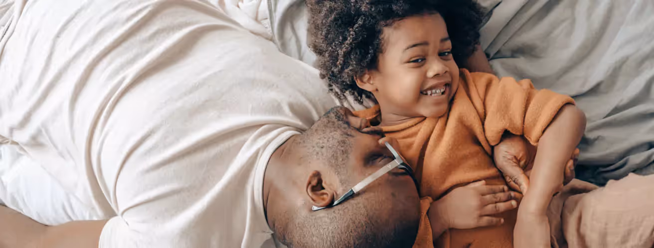 a dad with a kid laying on a sofa