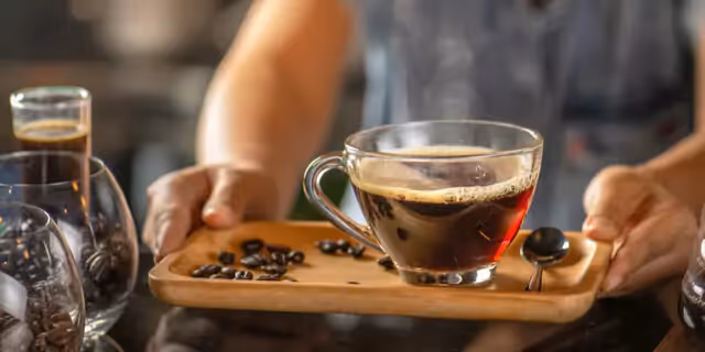 a person holding a tray with a cup of coffee