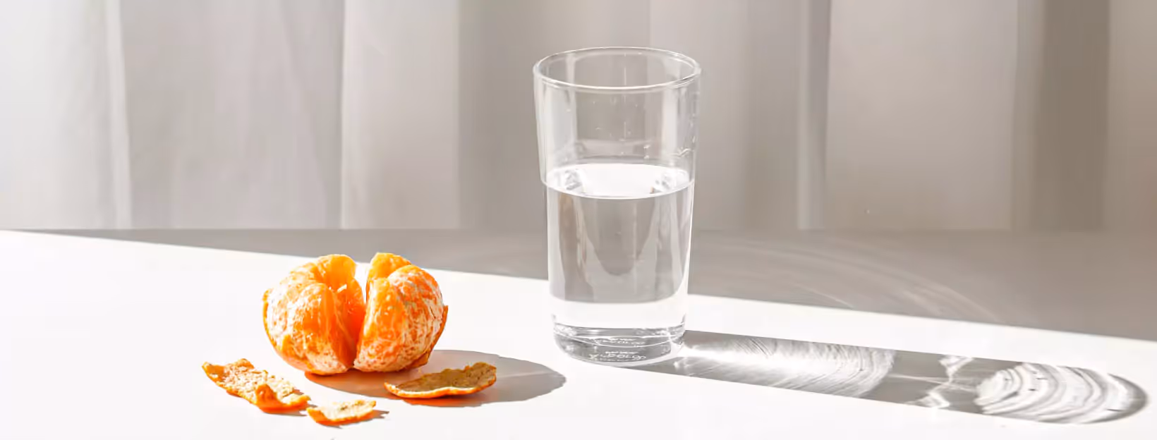 a glass of water and a mandarin orange