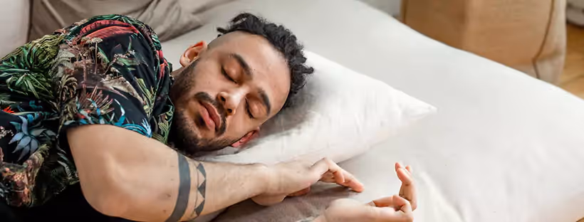 A man with curly hair in a colorful floral shirt, asleep