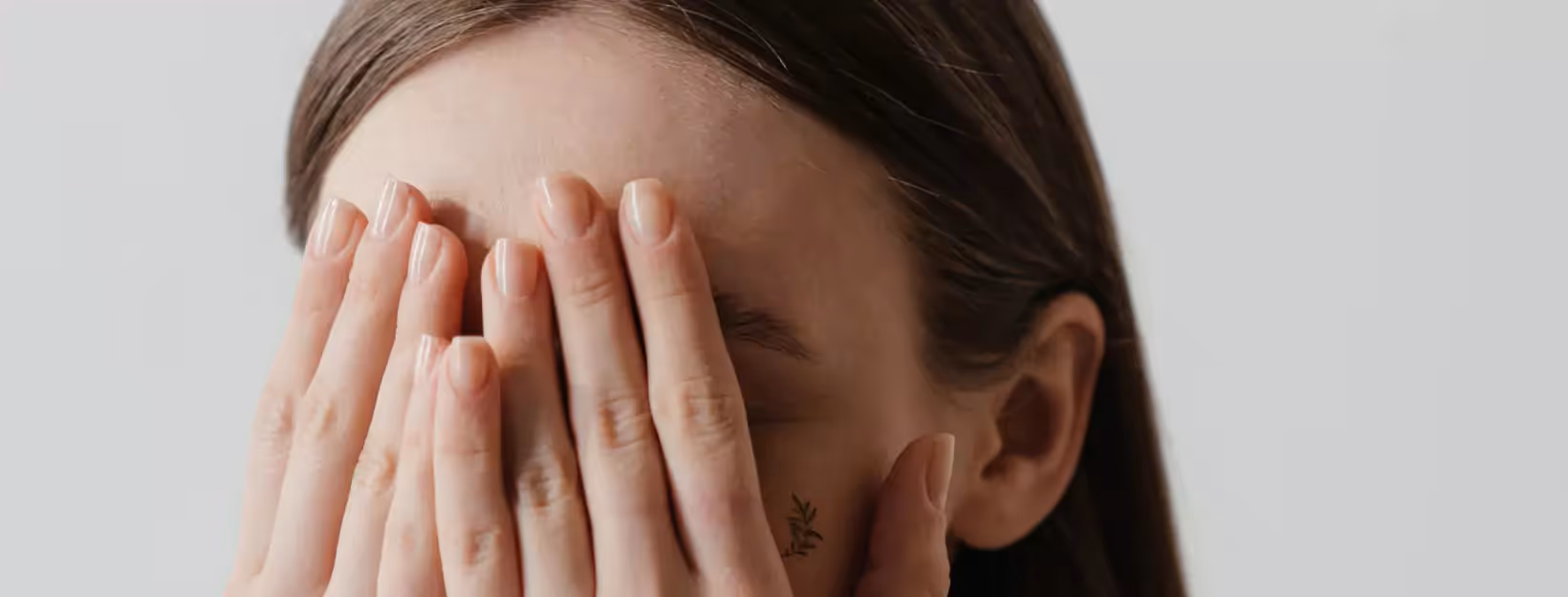 a person closing their eyes with their hands