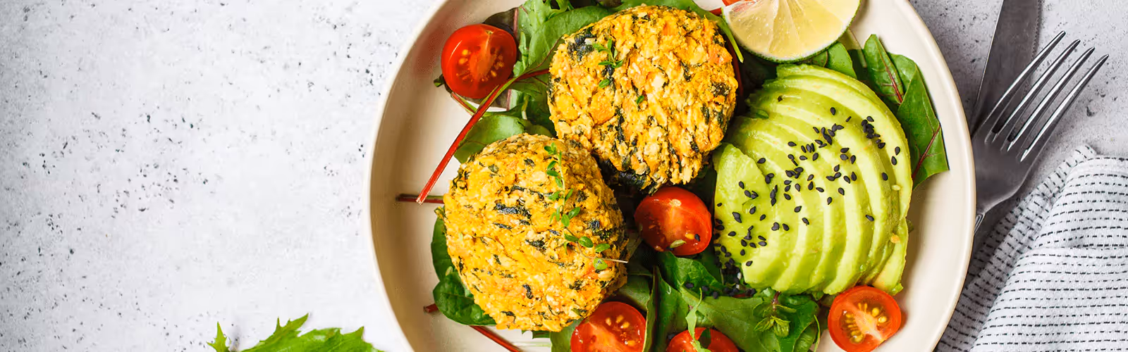 a plate of avocado, tomatoes, a slice of lemon