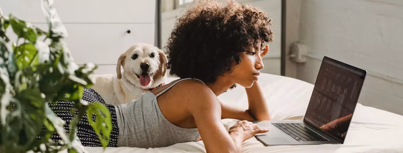 a person laying on bed and looking at a laptop
