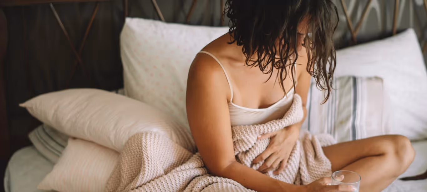a woman holding her stomach in bed