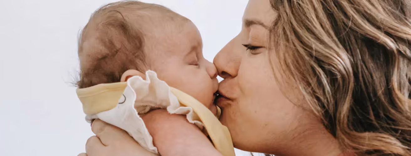 a mother kissing a baby