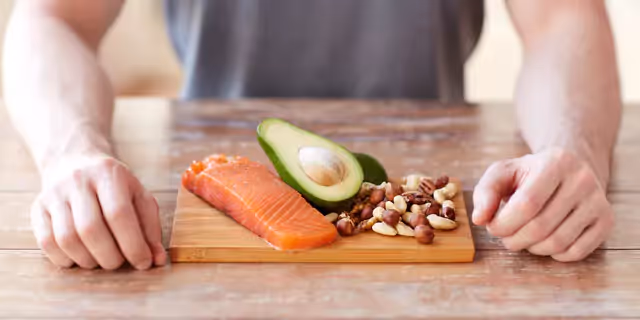 salmon an avocado and nuts on a wooden board