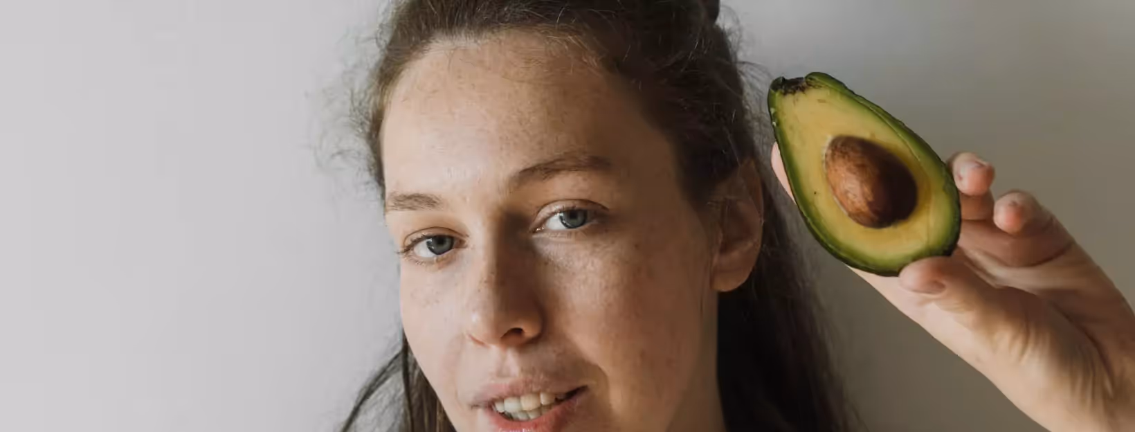 a person holding a half of the avocado