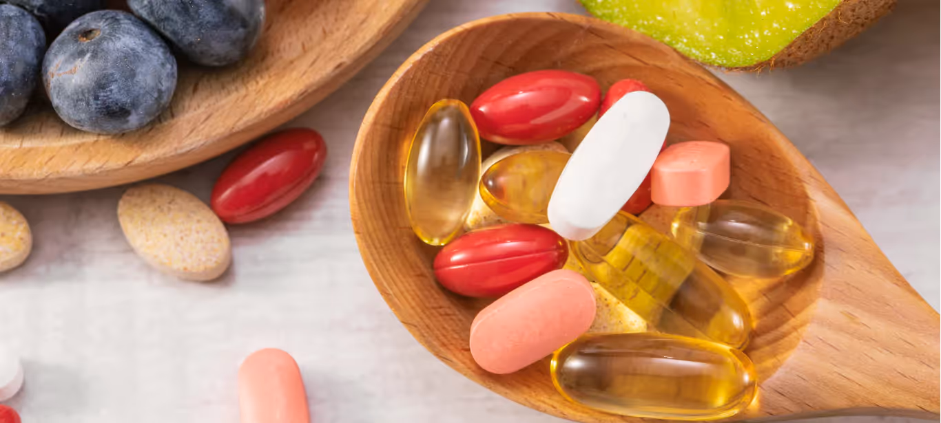 A wooden spoon filled with vitamin and mineral supplement pills