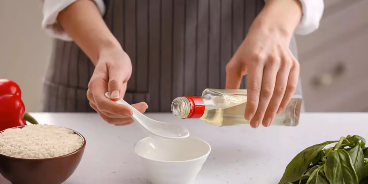 a person pouring the vinegar into a spoon