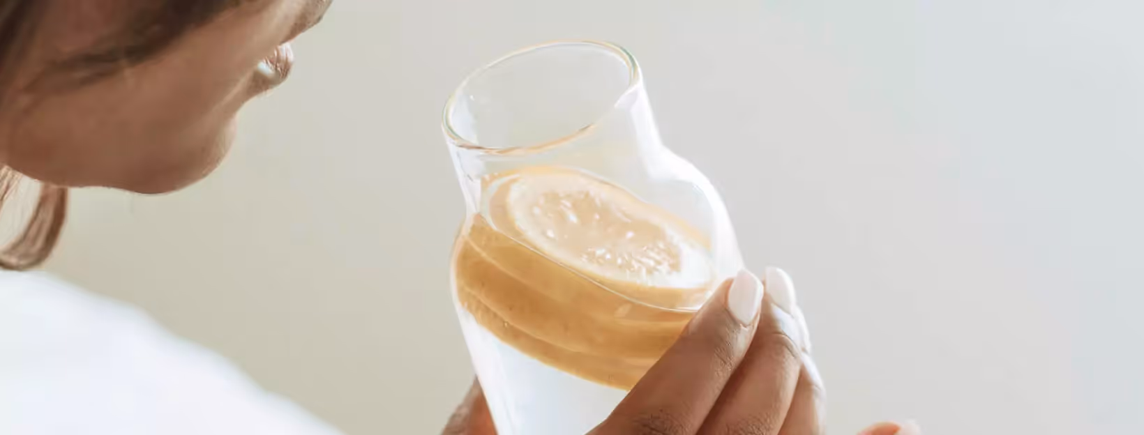 a person drinking water with lemon slices