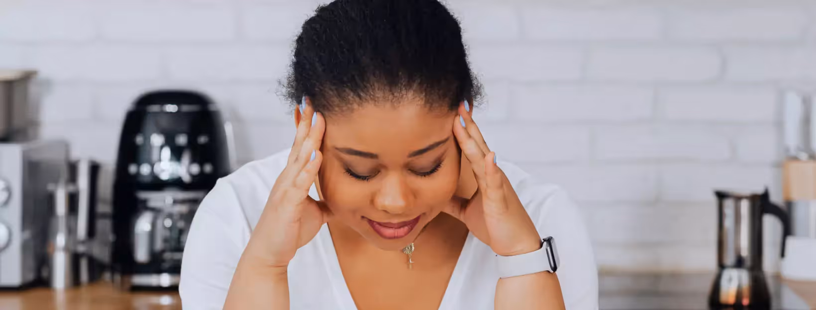 a person looking down and touch their head with their hands