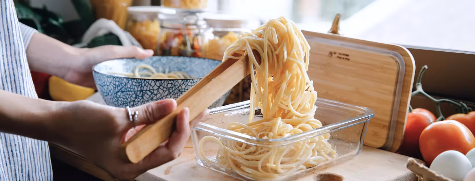 a person putting noodles into lunchbox