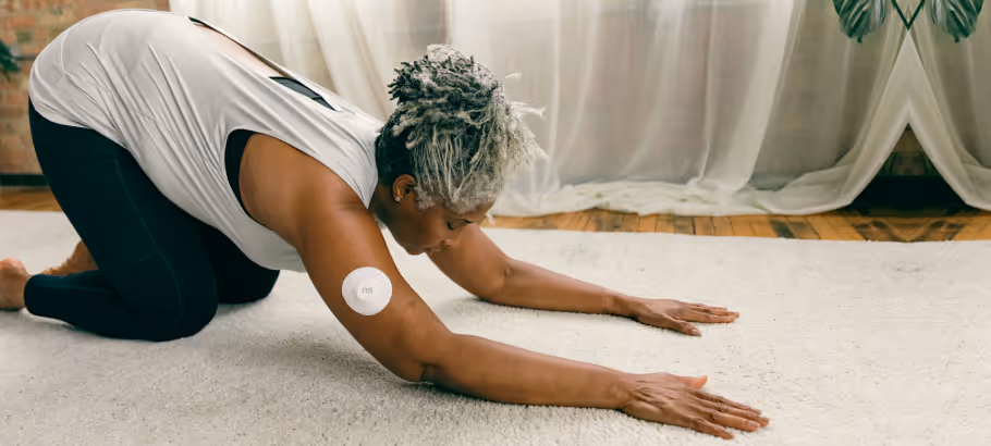 a woman doing yoga with a cgm patch