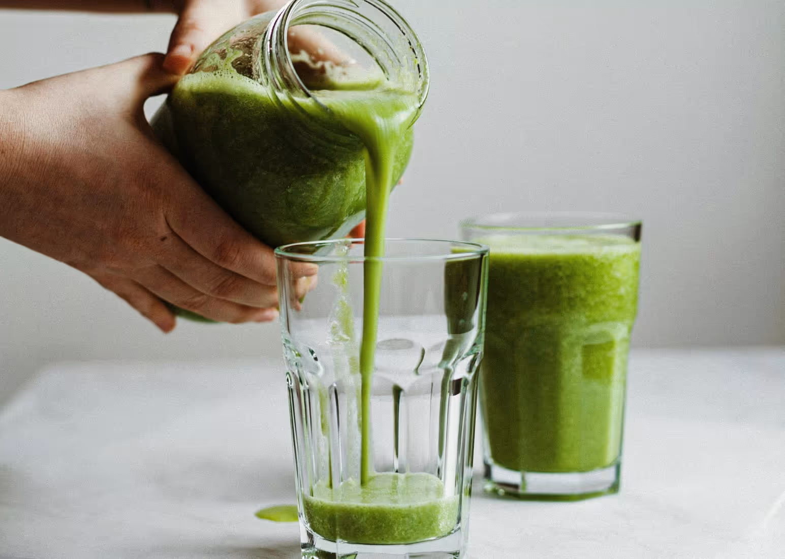 someone pouring a pitcher of greens powder