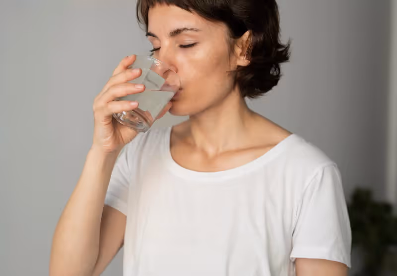 a woman drinking water and taking a pill