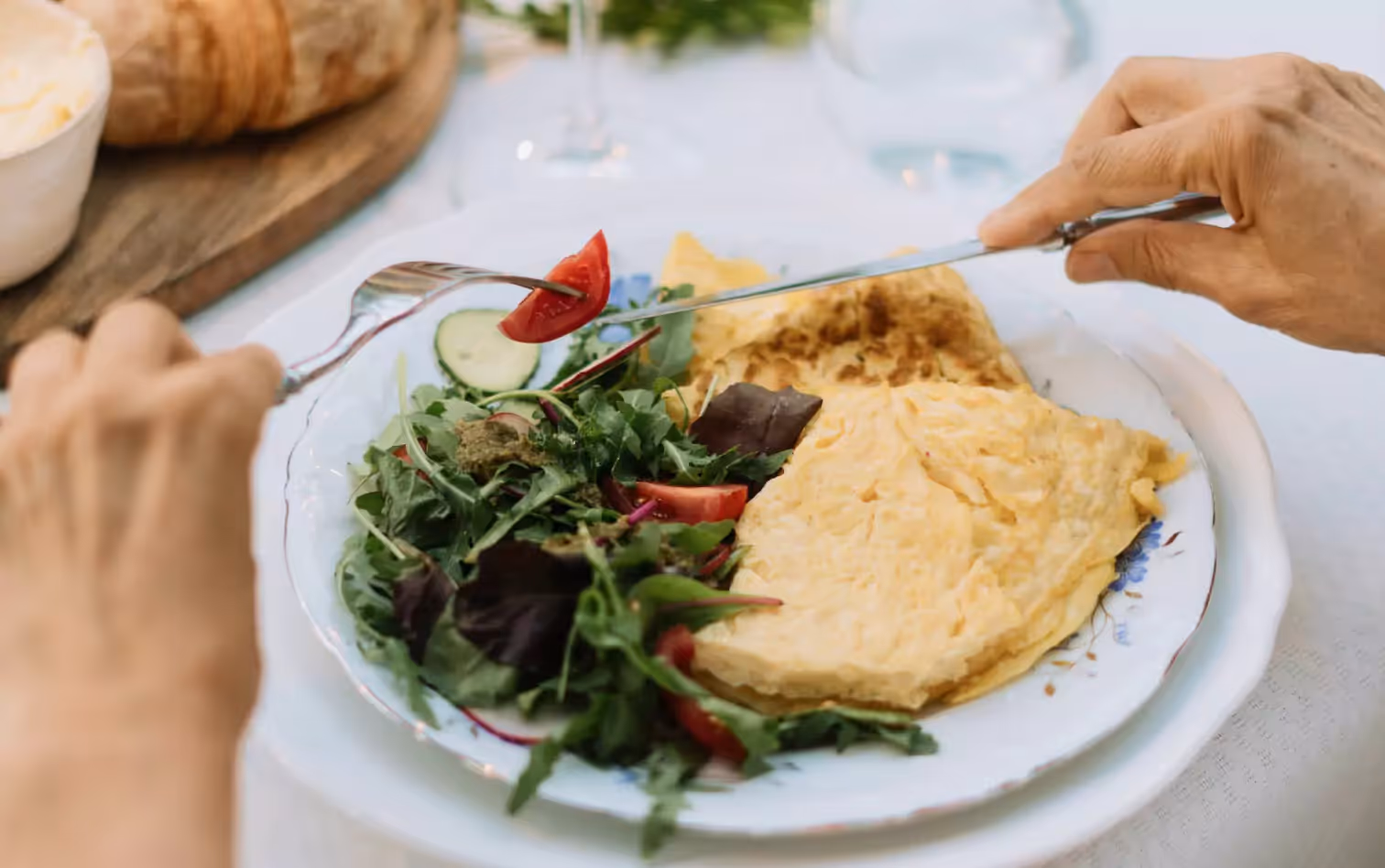 a person eating an omelette and a salad
