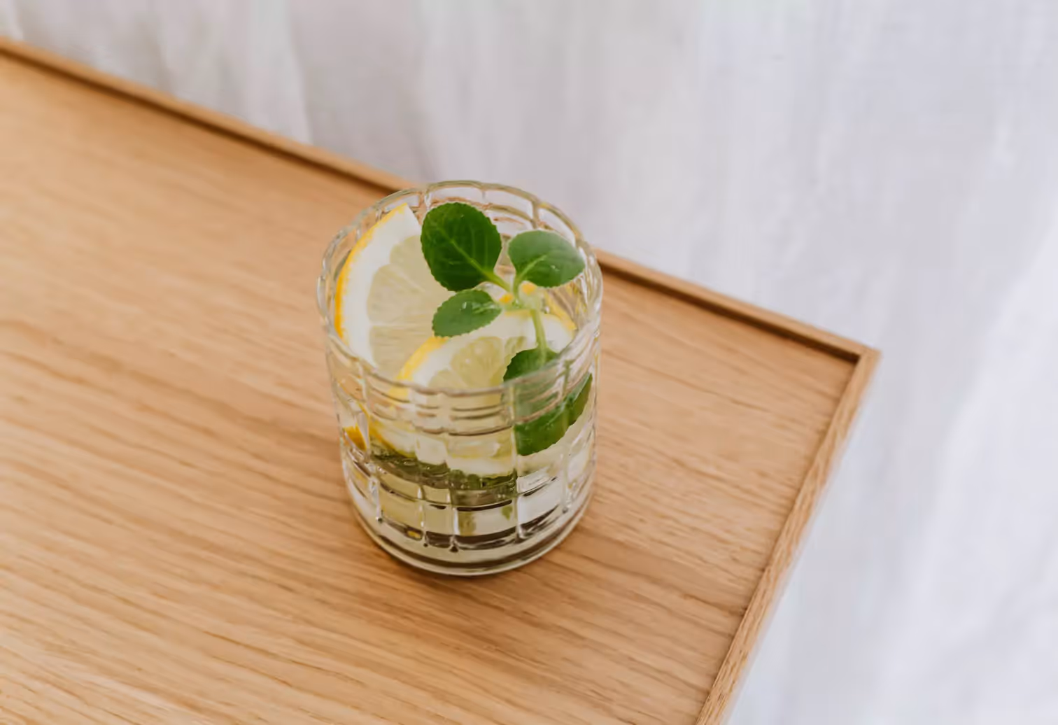 a glass of water with lemon slices and mint 