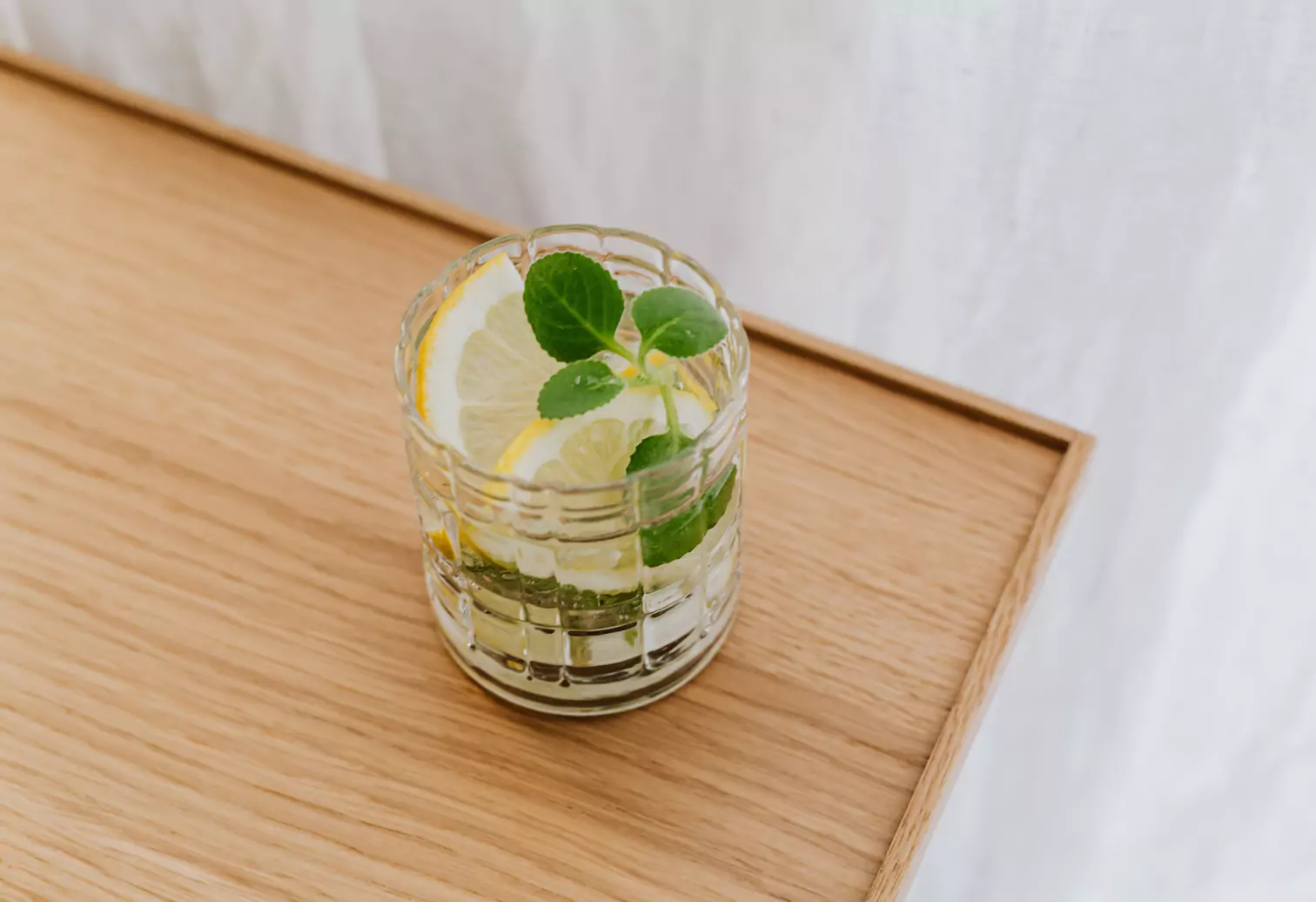 a glass of water with lemon slices and mint
