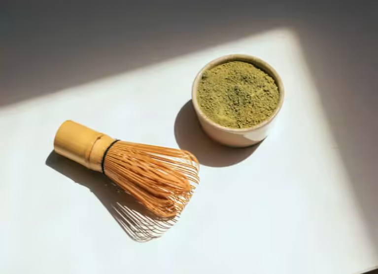 a bowl with matcha and a whisk