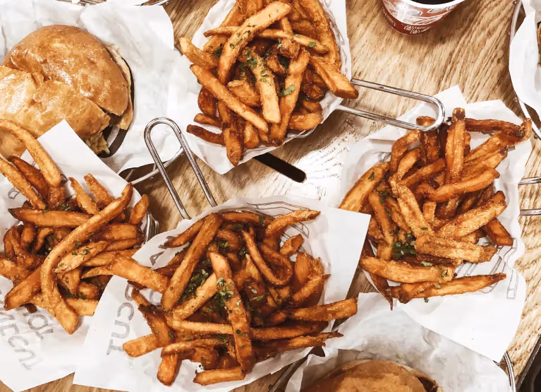 A dining table with burgers and fries